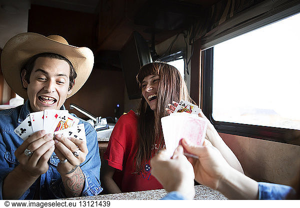 Friends enjoying while playing cards in camper van