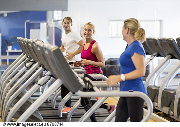Friends exercising on treadmills at health club