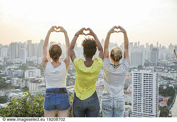 Friends gesturing heart shape in front of cityscape