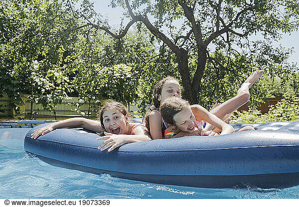 Friends having fun lying on pool raft in swimming pool