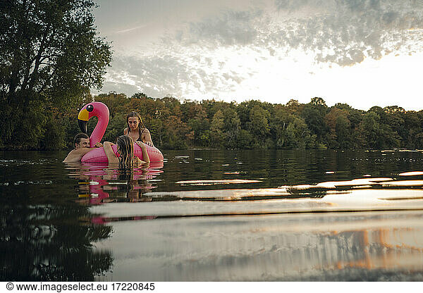 Friends having fun on a lake on a pink flamingo floating tire