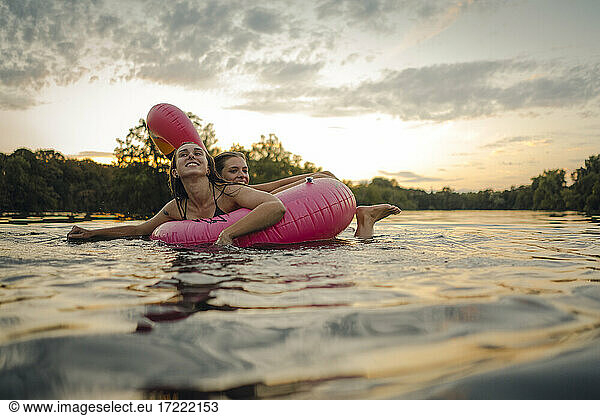 Friends having fun on a lake on a pink flamingo floating tire