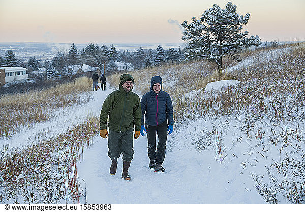 Friends hike snow-covered trail at dusk above Boulder  Colorado