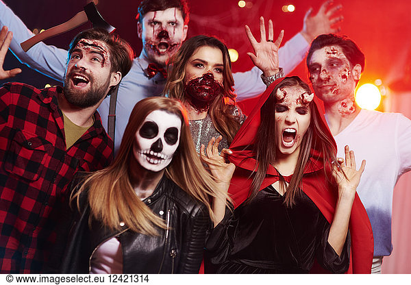 Friends in creepy costumes having fun at Halloween party