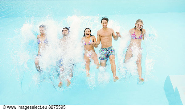 Friends jumping into swimming pool