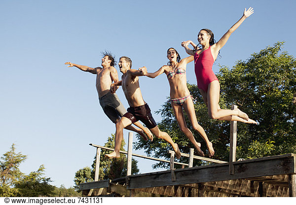 Friends jumping off dock