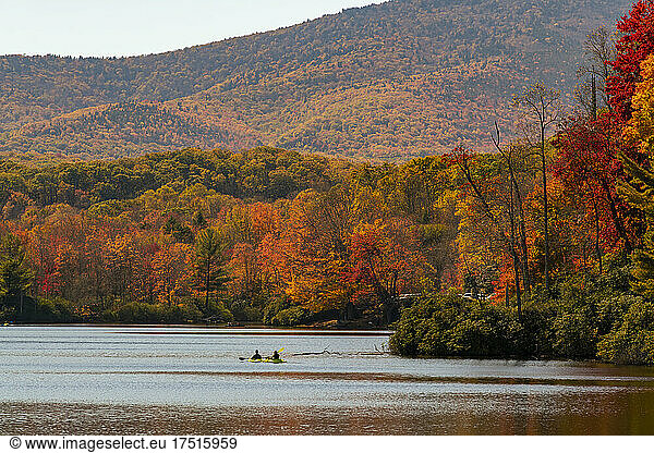 Friends kayaking in lake by autumn trees in forest
