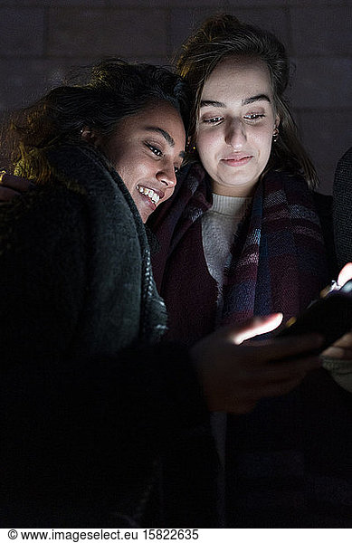 Friends looking at illuminated smartphones in the dark
