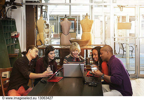 Friends looking at laptop while sitting in clothing store