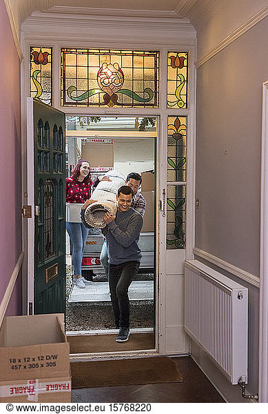 Friends moving house  carrying rug through front door