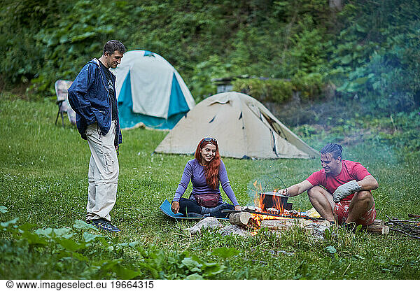 friends near bonfire in camping zone
