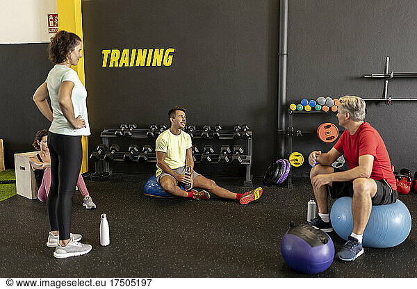 Friends relaxing and talking in gym