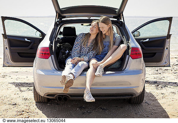 Friends relaxing in car trunk at beach