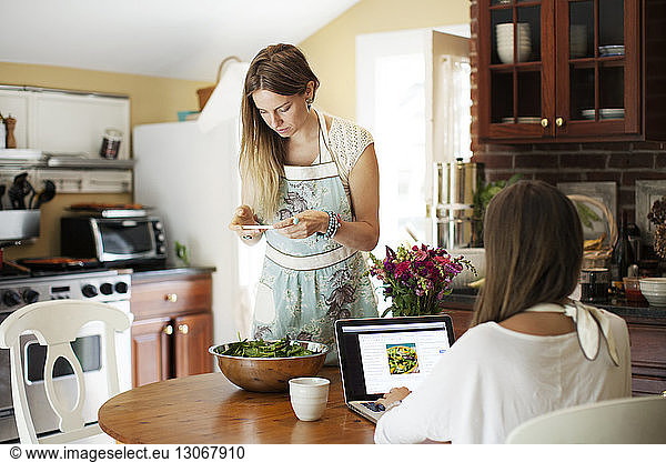 Friends searching recipe while preparing food at home