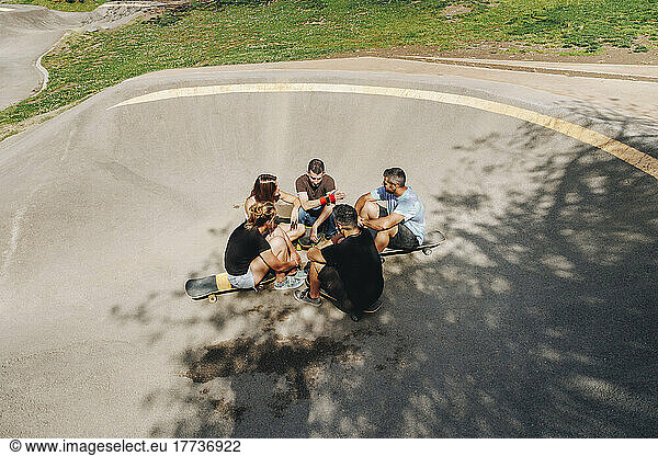 Friends sitting on ramp talking at skateboard park