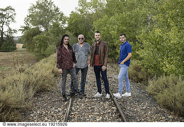 Friends standing on railroad tracks amidst plants