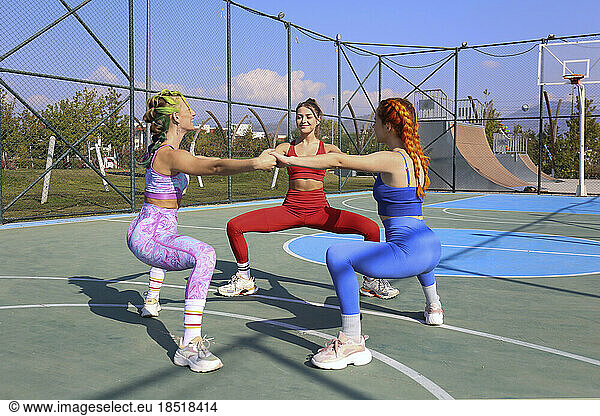 Friends stretching together on basketball court
