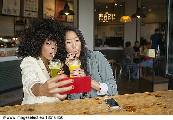 Friends taking selfie drinking healthy juice at cafe
