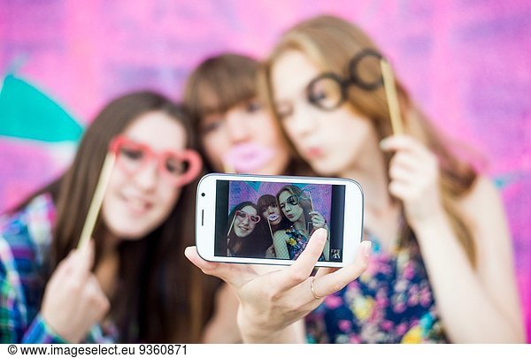 Friends taking selfie wearing fake spectacles and lips