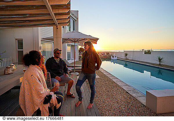 Friends talking at sunny patio poolside at sunset