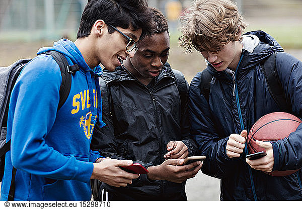 Friends talking while looking at smart phone on playing field