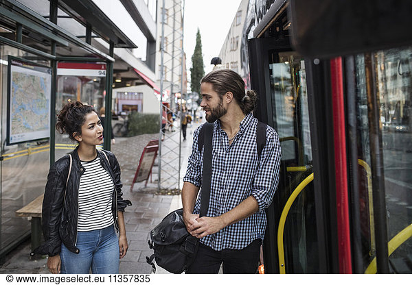 Friends talking while standing by bus in city
