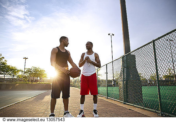 Friends talking while standing in basketball court