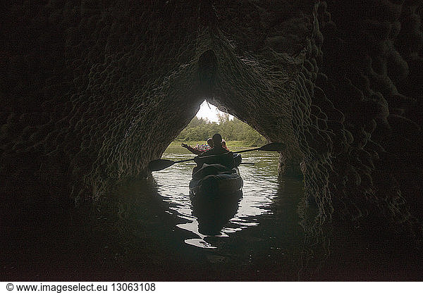 Friends travelling in boat on river at cave