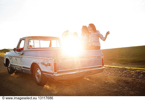 Friends travelling in pick-up truck during sunset