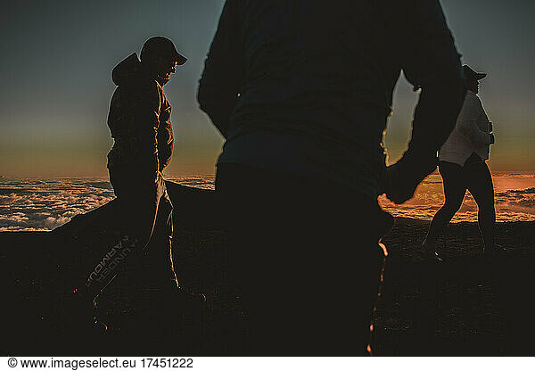 Friends walk around at sunset on top of Mauna Kea