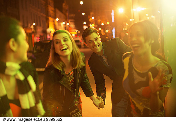 Friends walking down city street together at night