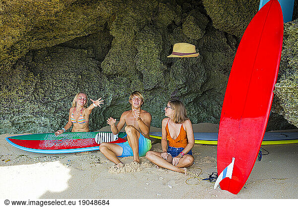 Friends with surfboards on the beach.