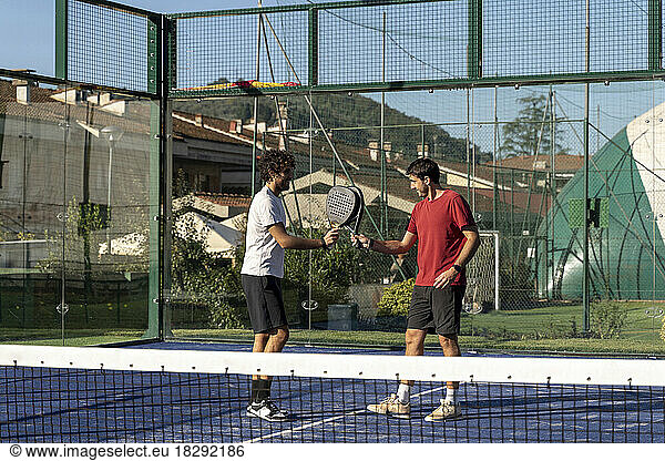 Friends with tennis rackets playing at sports court