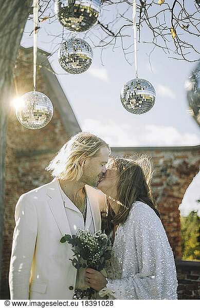 Frisch verheiratetes Paar küsst sich auf den Mund unter Discokugeln bei der Hochzeit