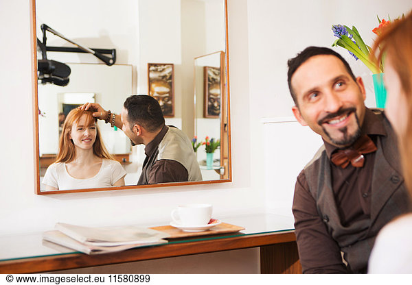 Friseur berät Kunden über Frisur im Salon