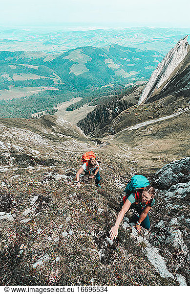 Front shot of women ascending steep cliff in Swiss alps