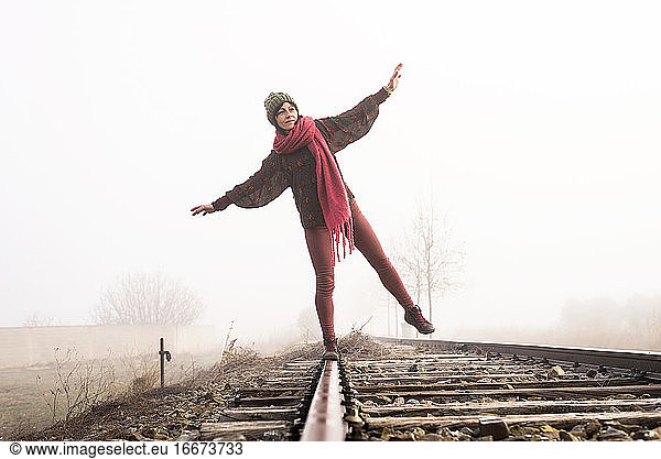 Front view of a girl balancing on train rail while walking