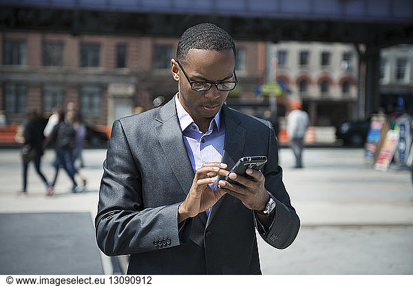 Front view of businessman using smart phone on street