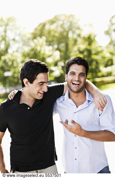 Front view of cheerful male friends with arm around