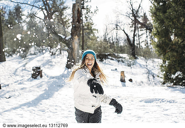 Front view of cheerful woman playing with snow in field