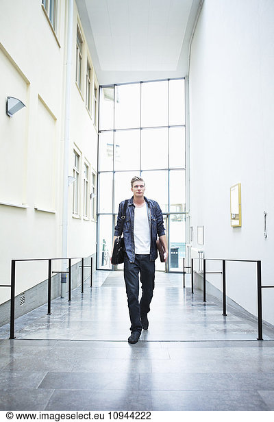 Front view of confident young man walking carrying bag