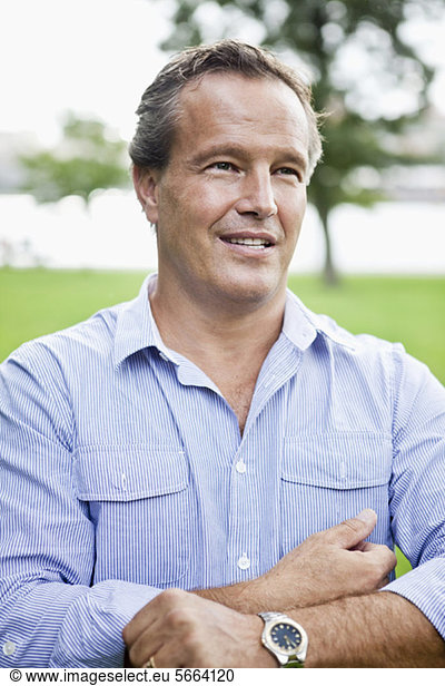 Front view of mature businessman rolling up sleeves outdoors