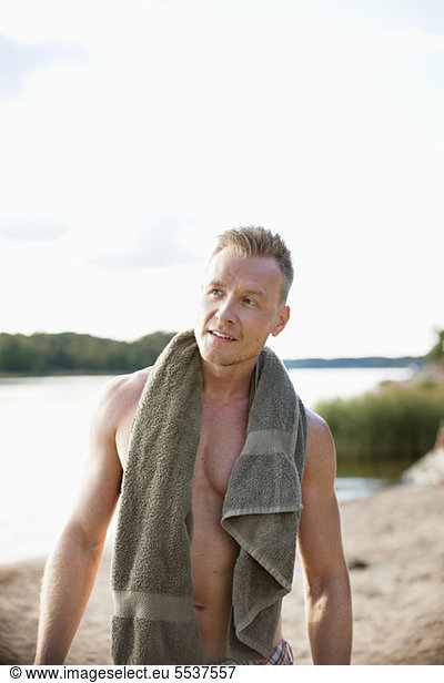 Front view of mid adult man with towel on beach