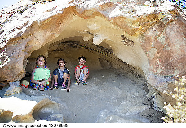 Front view of siblings sitting in cave