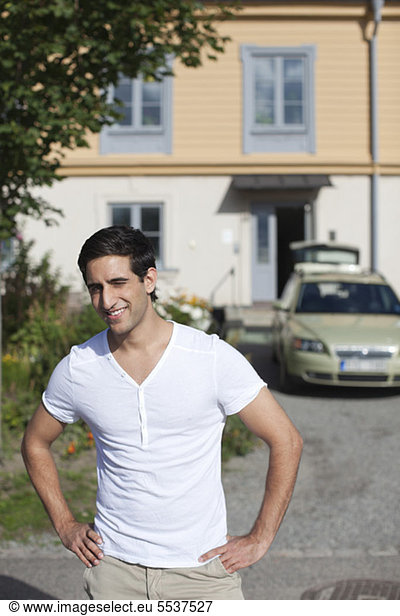 Front view of young man with car in background