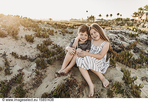 Front view of young redheaded freckled siblings sitting at beach