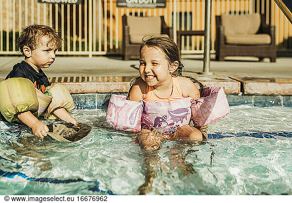 Front view of young siblings playing in pool on vacation in California