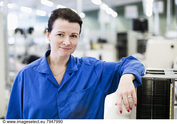 Front view portrait of confident female technician standing in industry