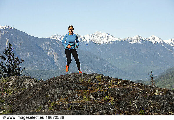 Frontansicht einer starken Sportlerin  die beim Fitnesstraining auf dem Lande gegen einen verschneiten Bergkamm läuft