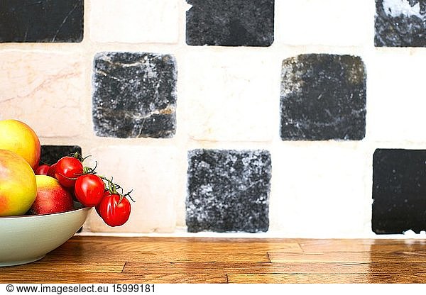 Fruit and vegetables on the kitchen top near tiled wall  tomatoes and apples  cozy design space for text.
